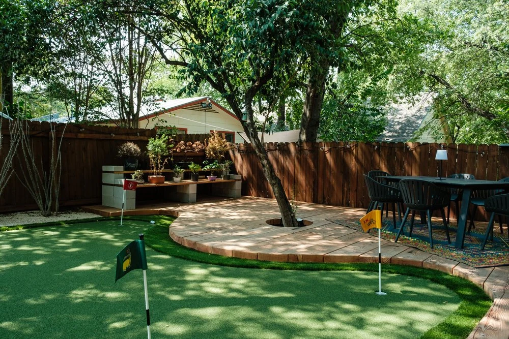 Backyard putting green beside a rounded dining patio under a tree