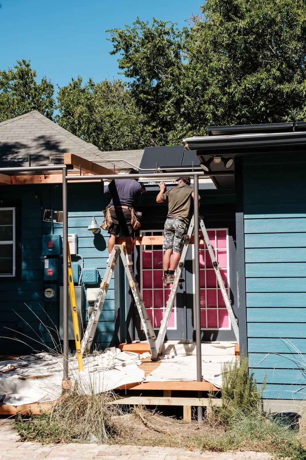 Two crew members positioning and checking a beam during outdoor construction