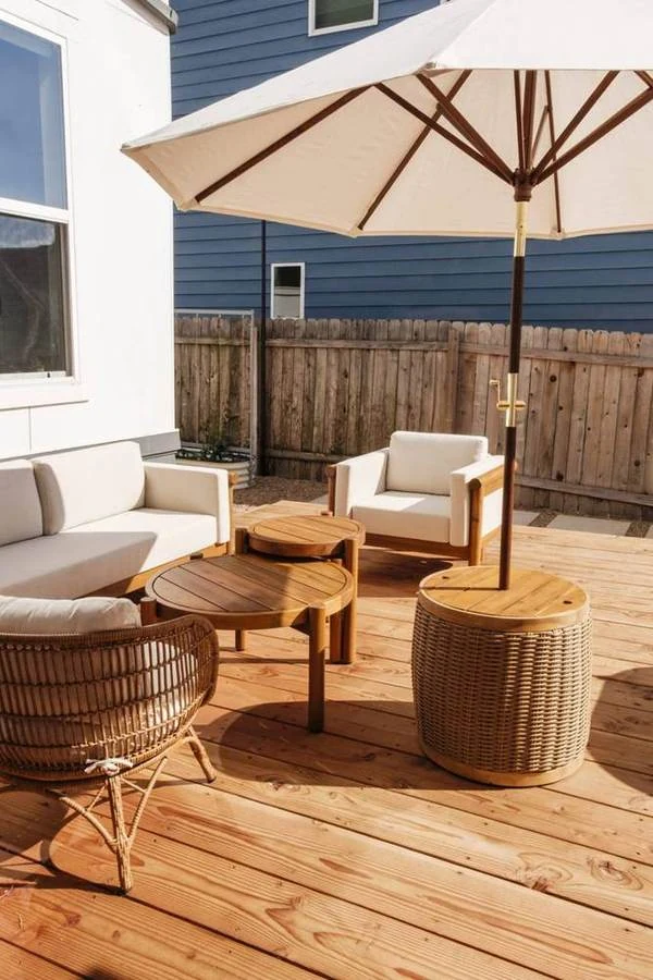 Lounge seating and a sun umbrella on a wood deck beside the home