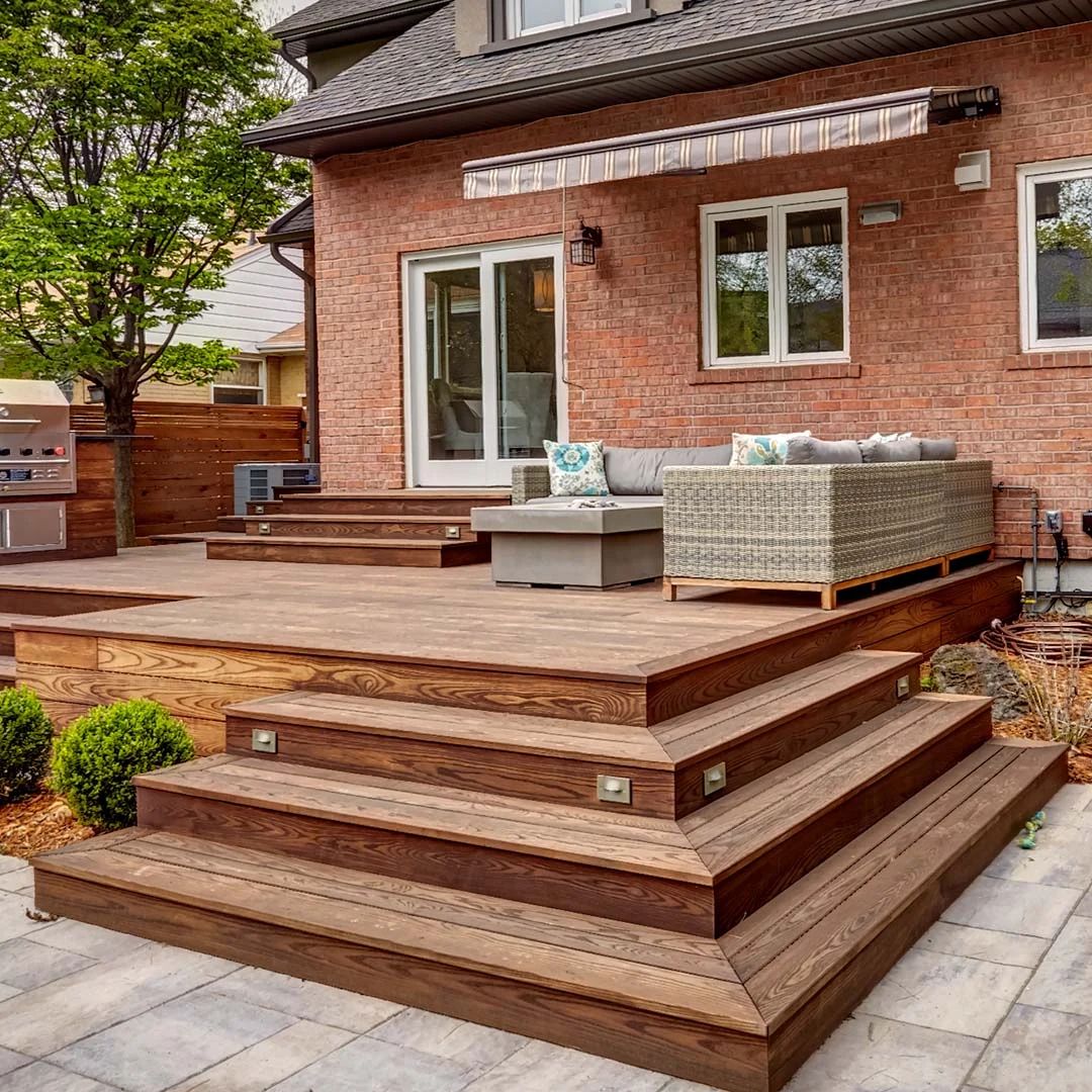 Warm Thermory ash decking and mitered steps beside a brick house